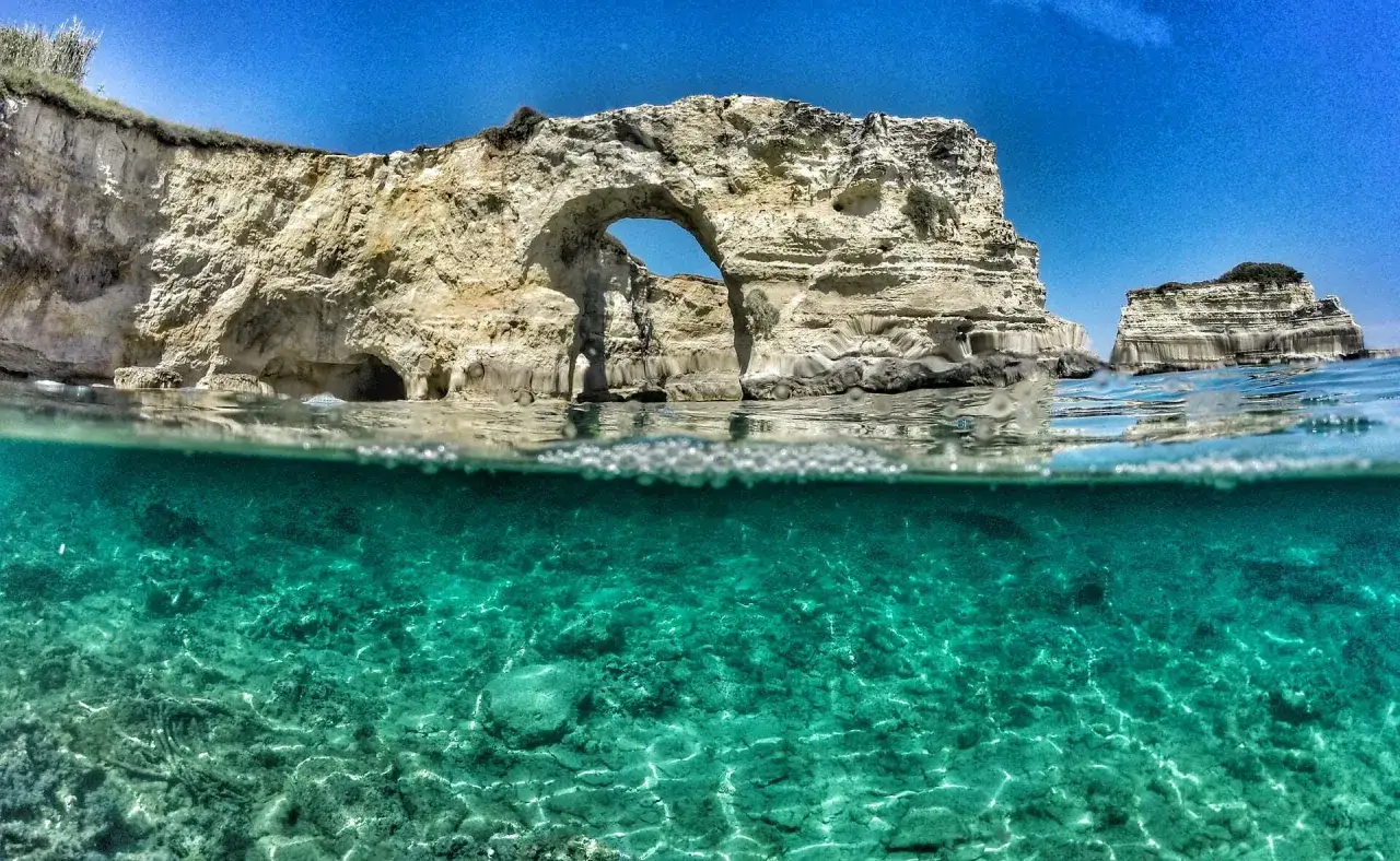 Arco naturale e faraglioni nel mare cristallino del Salento, Puglia. Un paradiso subacqueo.