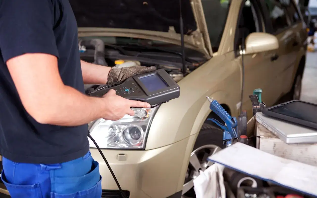 Mechanik diagnozuje rozkodowane wtryski objawy za pomocą testera diagnostycznego przy złotym samochodzie.
