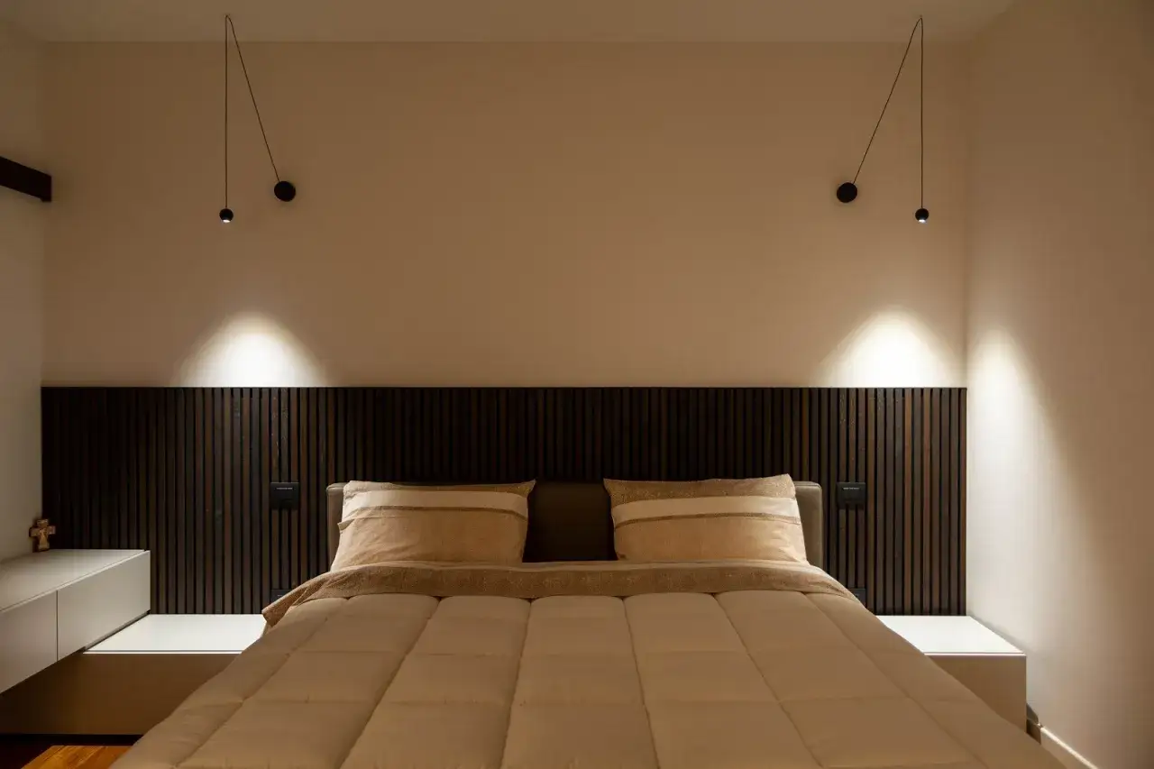 Camera da letto moderna con testiera in legno scuro e controsoffittatura che valorizza l'illuminazione.