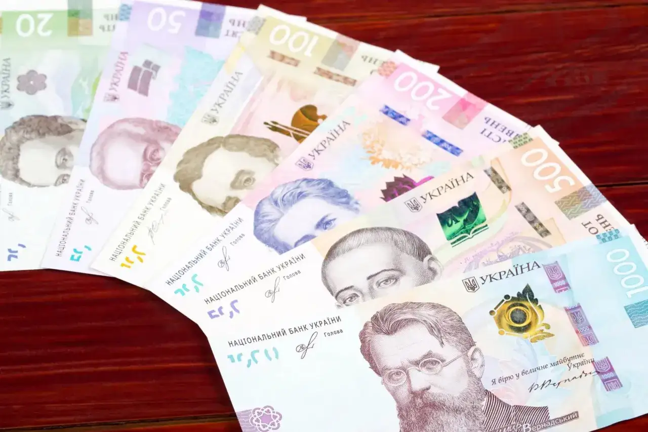 Ukraińskie hrywny, czyli jaka waluta jest w Ukrainie, ułożone wachlarzowo na drewnianym tle. Widoczne nominały: 20, 50, 100, 200, 500, 1000.