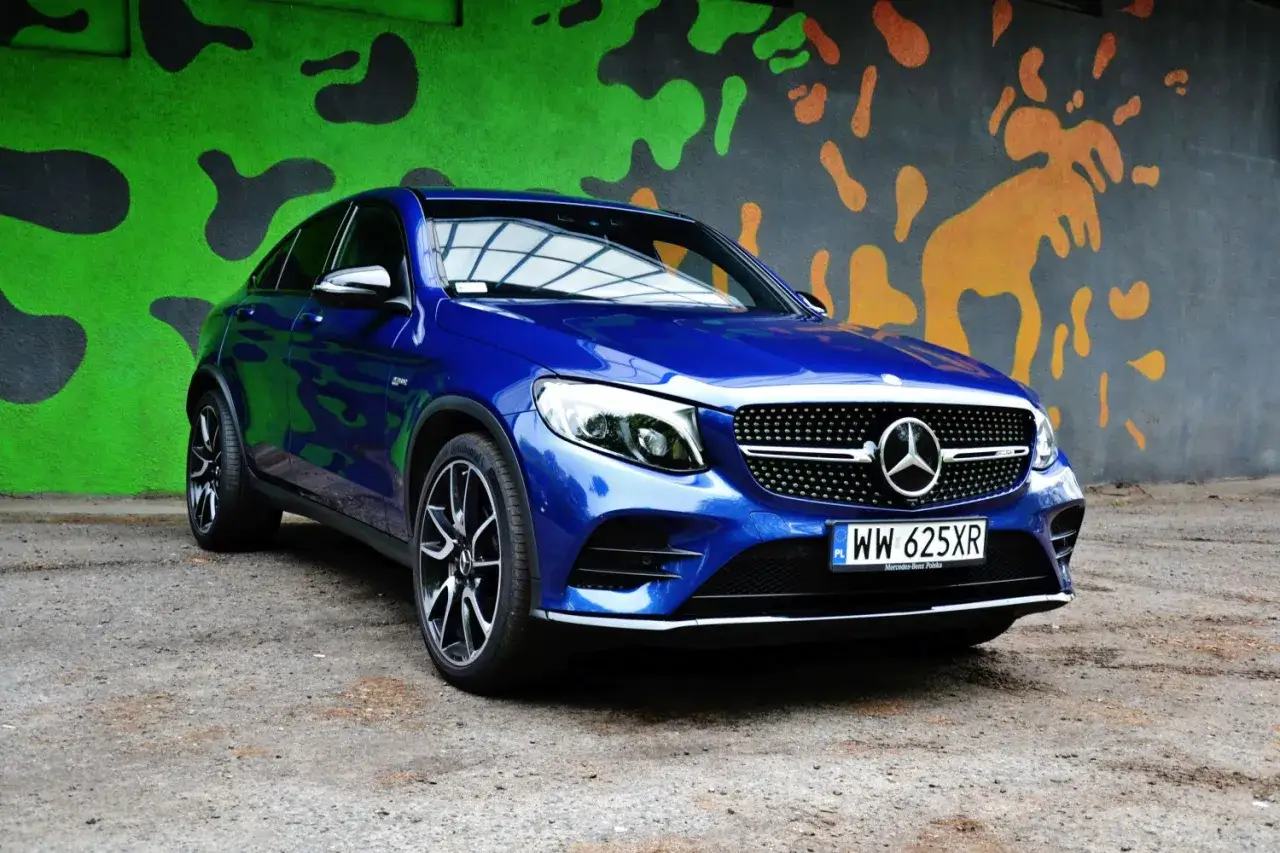 Błękitny Mercedes-Benz GLC **coupe** na tle kolorowego, abstrakcyjnego muralu.