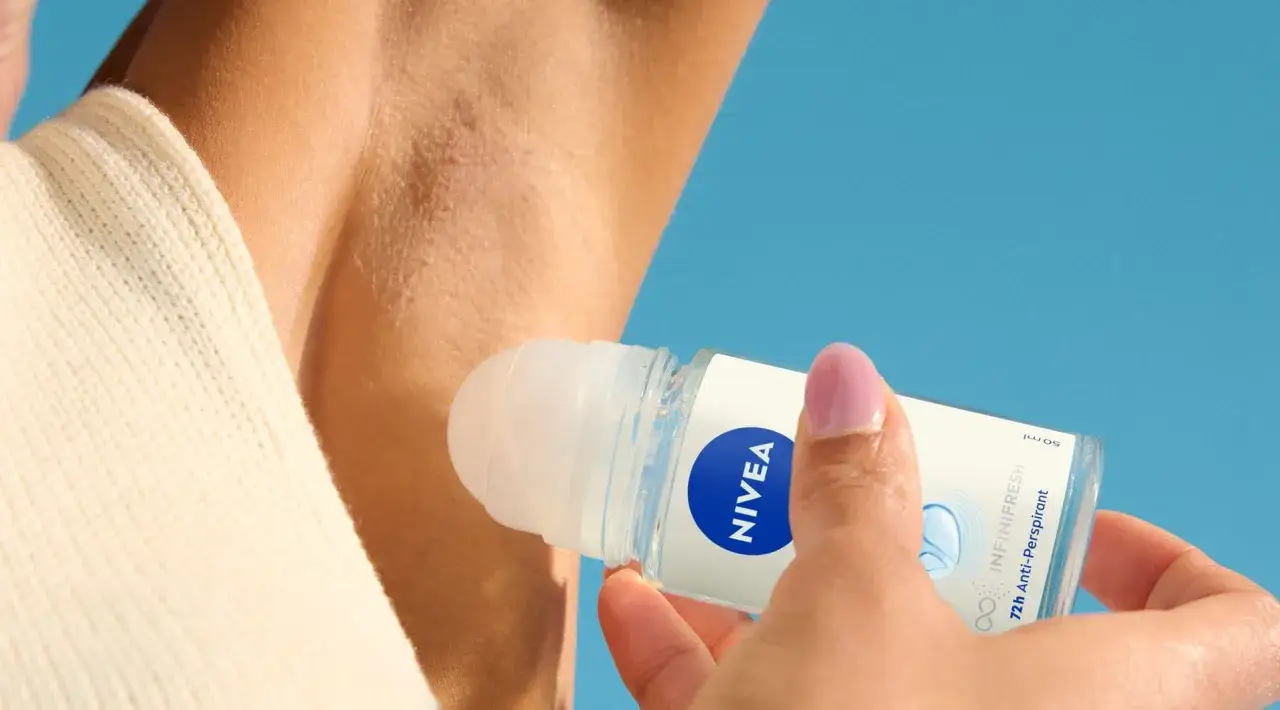 Dłoń aplikuje antyperspirant Nivea pod pachę, by skutecznie jak pozbyc sie zapachu potu.