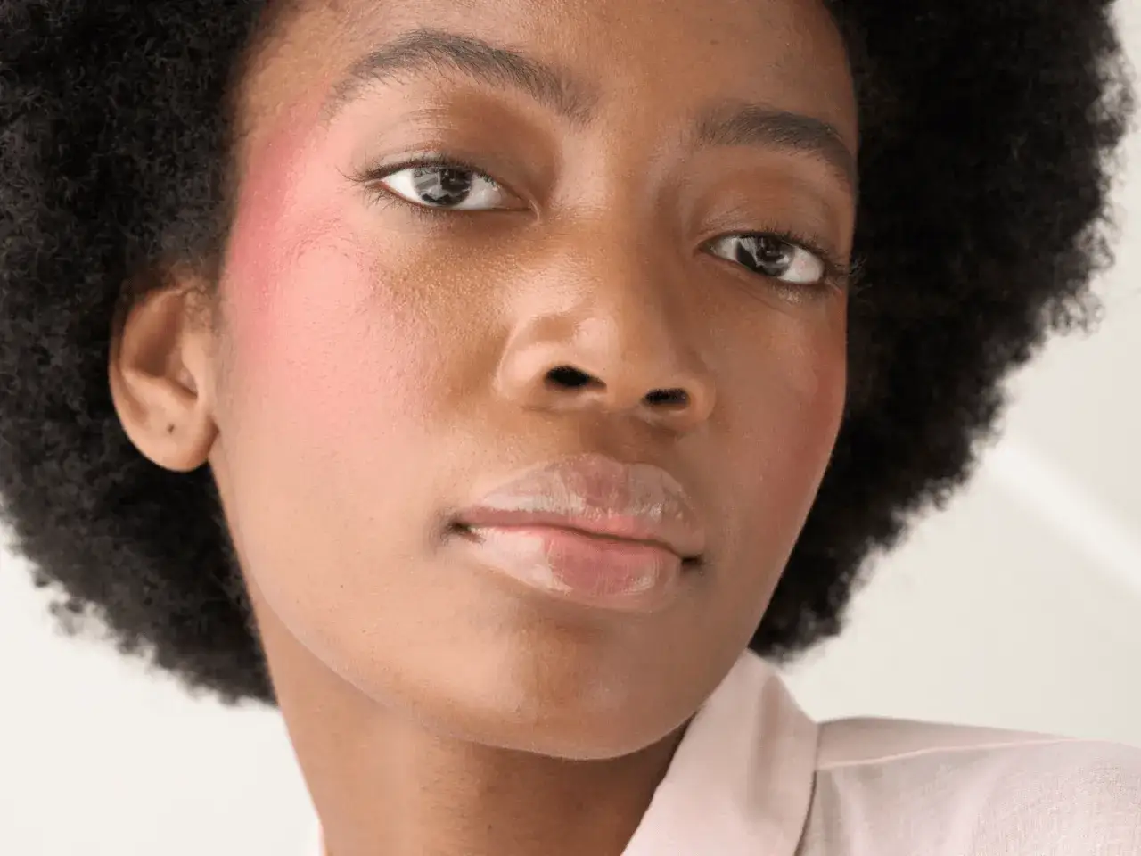 Rostro de mujer con un toque de blush rosado en las mejillas, resaltando su belleza natural.