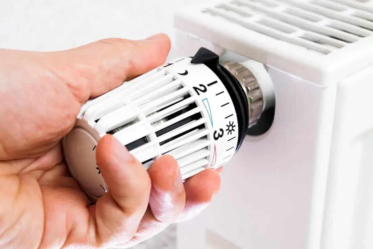 Hand dreht am Thermostatventil, das auf Stufe 2 steht. Es scheint, als ob der Thermostat defekt ist, da die Heizung nicht richtig funktioniert.