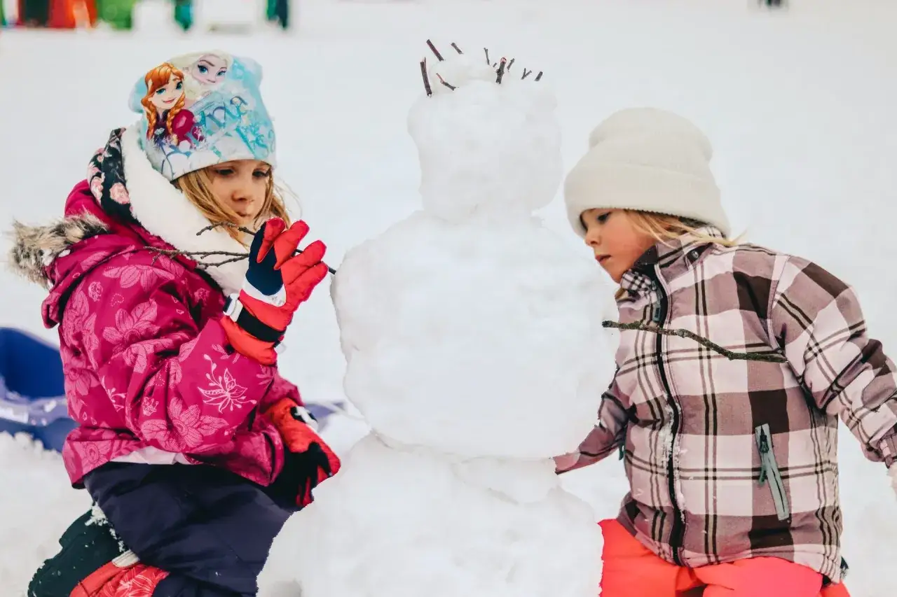 Bambini creano un pupazzo di neve in montagna, un magico natale in montagna con bambini.