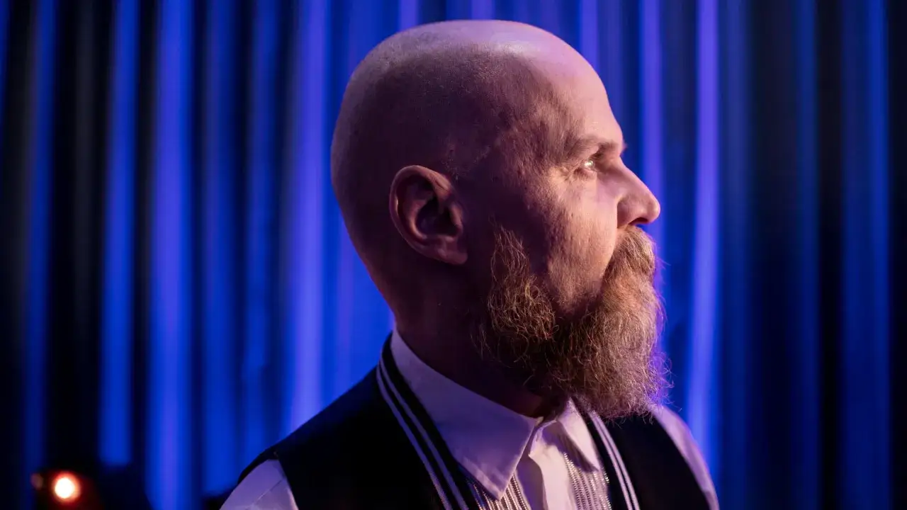 Alexander Bard, med rakad skalle och sk&auml;gg, blickar ut mot ett bl&aring;tt rid&aring;.