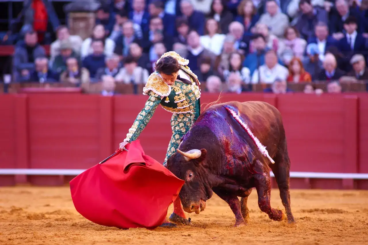 Juan Antonio Ruiz Espartaco, torero, se enfrenta a un toro bravo en la arena. El p&uacute;blico observa atento.