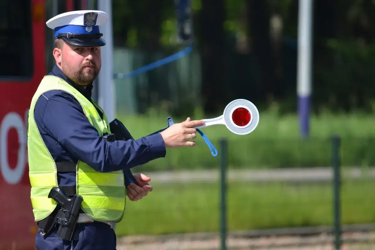 Policjant z lizakiem w ręku, gotowy do zatrzymania pojazdu. Kierowco, uważaj, bo możesz dostać 10 punktów karnych!