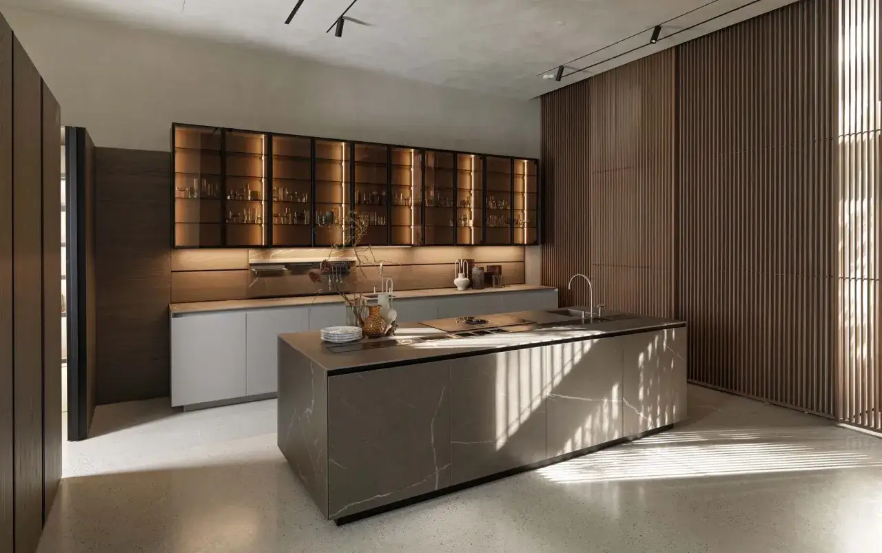 Cocina moderna con isla central y armarios iluminados. La luz c&aacute;lida de los armarios y la luz natural que entra por la ventana crean un ambiente acogedor, demostrando que **que luz es mejor para la cocina** depende del ambiente deseado.