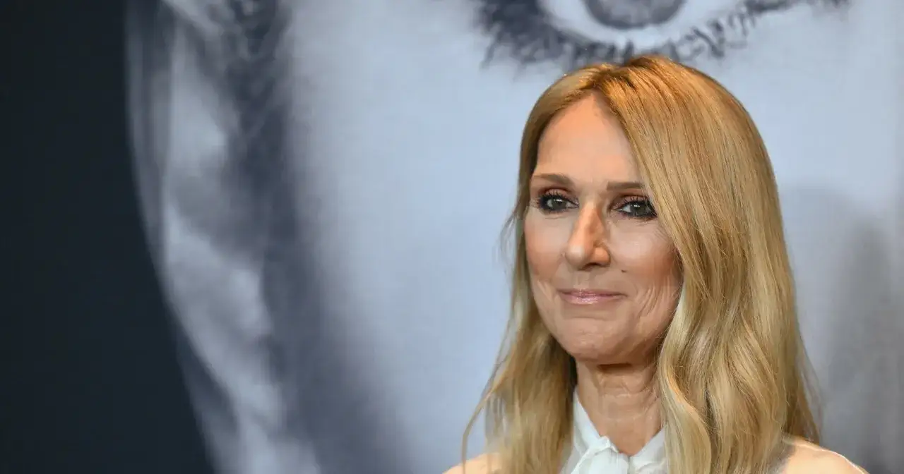 Celine Dion z uśmiechem na twarzy, w tle wielkoformatowy portret.