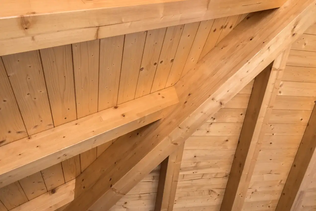 Close-up of a wooden house framing, showing the intricate structure of beams and planks, creating a warm and natural aesthetic.