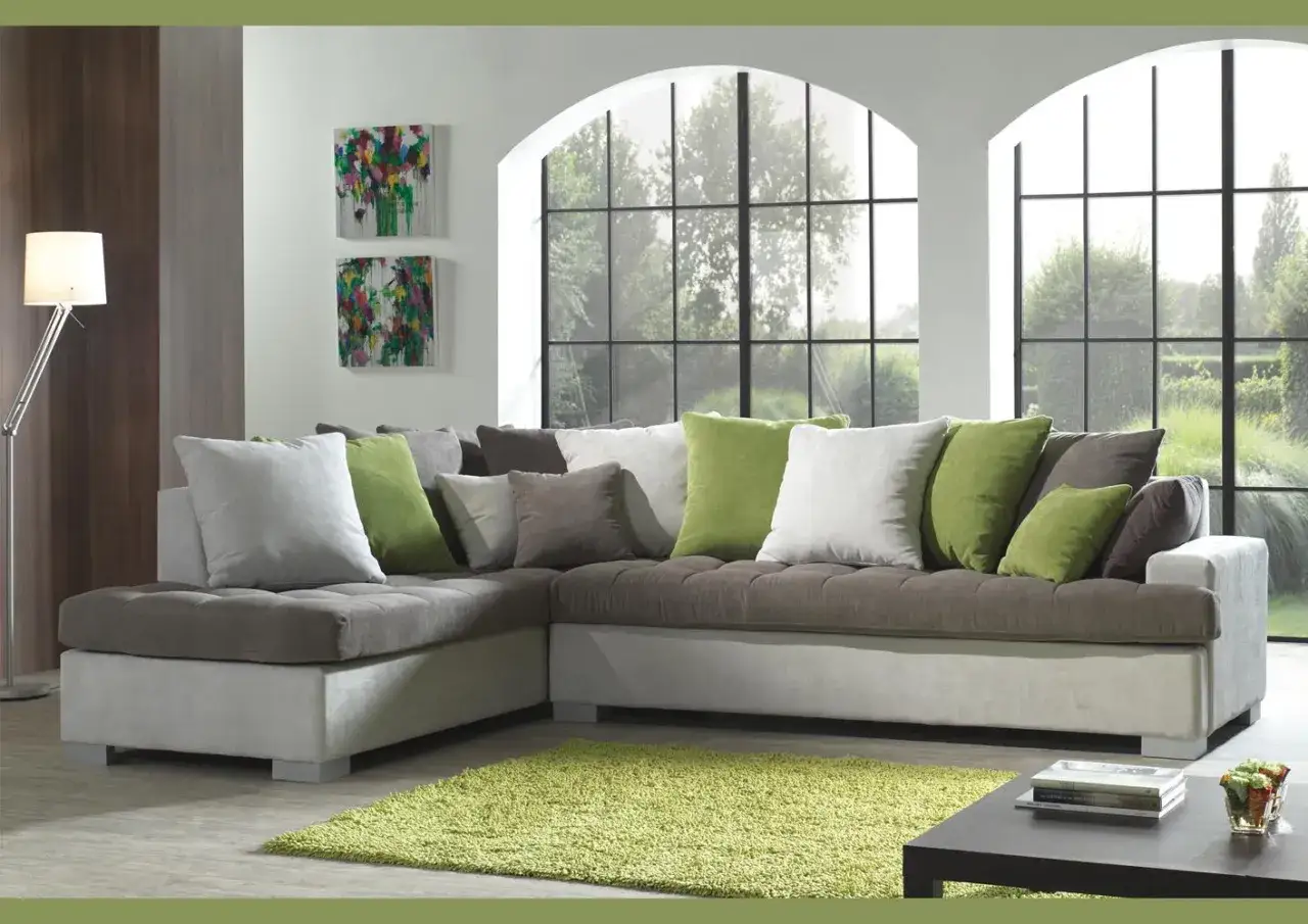 Comment disposer des coussins sur un canap&eacute; d'angle : un m&eacute;lange de gris, blanc et vert pour un look cosy.