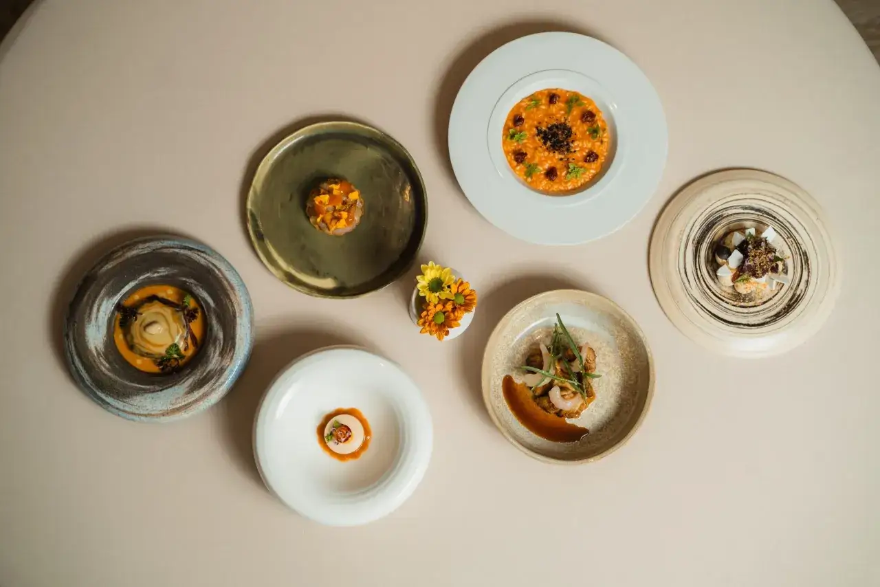 Sześć wykwintnych dań, jak z restauracji gwiazdki Michelin, ułożonych na jasnym stole. Każde danie to małe dzieło sztuki.