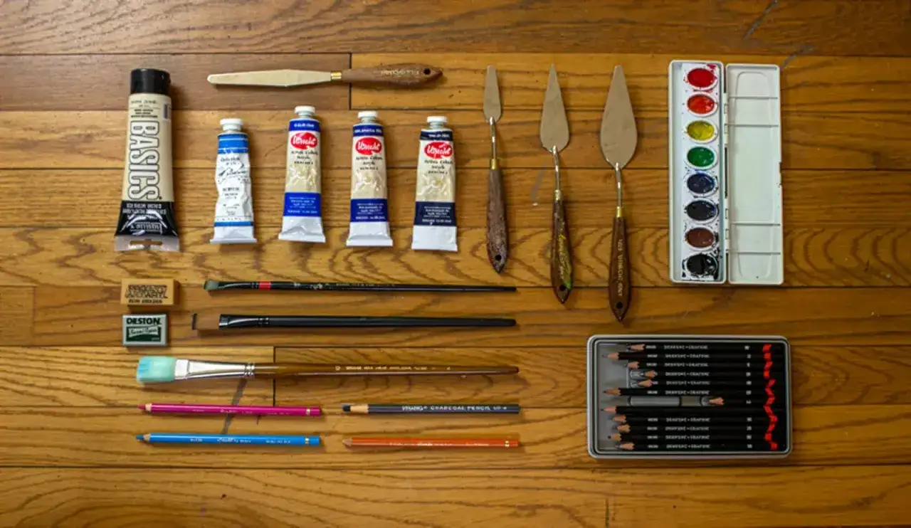 Mat&eacute;riel de paysage : tubes de peinture, pinceaux, couteaux &agrave; palette, crayons et aquarelles, pr&ecirc;ts pour une cr&eacute;ation artistique.