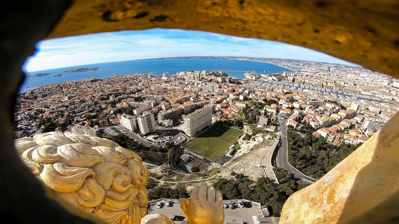 Vue a&eacute;rienne de Marseille depuis la basilique Notre-Dame de la Garde, avec le Vieux-Port et la mer en arri&egrave;re-plan.
