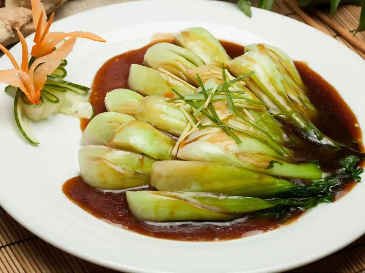 Sałata pak choi w sosie, udekorowana kwiatkiem z marchewki i plasterkami ogórka.