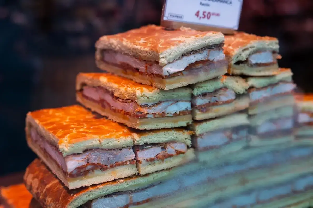Porciones de hornazo de Pascua, un pastel salado relleno de carne, apiladas en un escaparate.