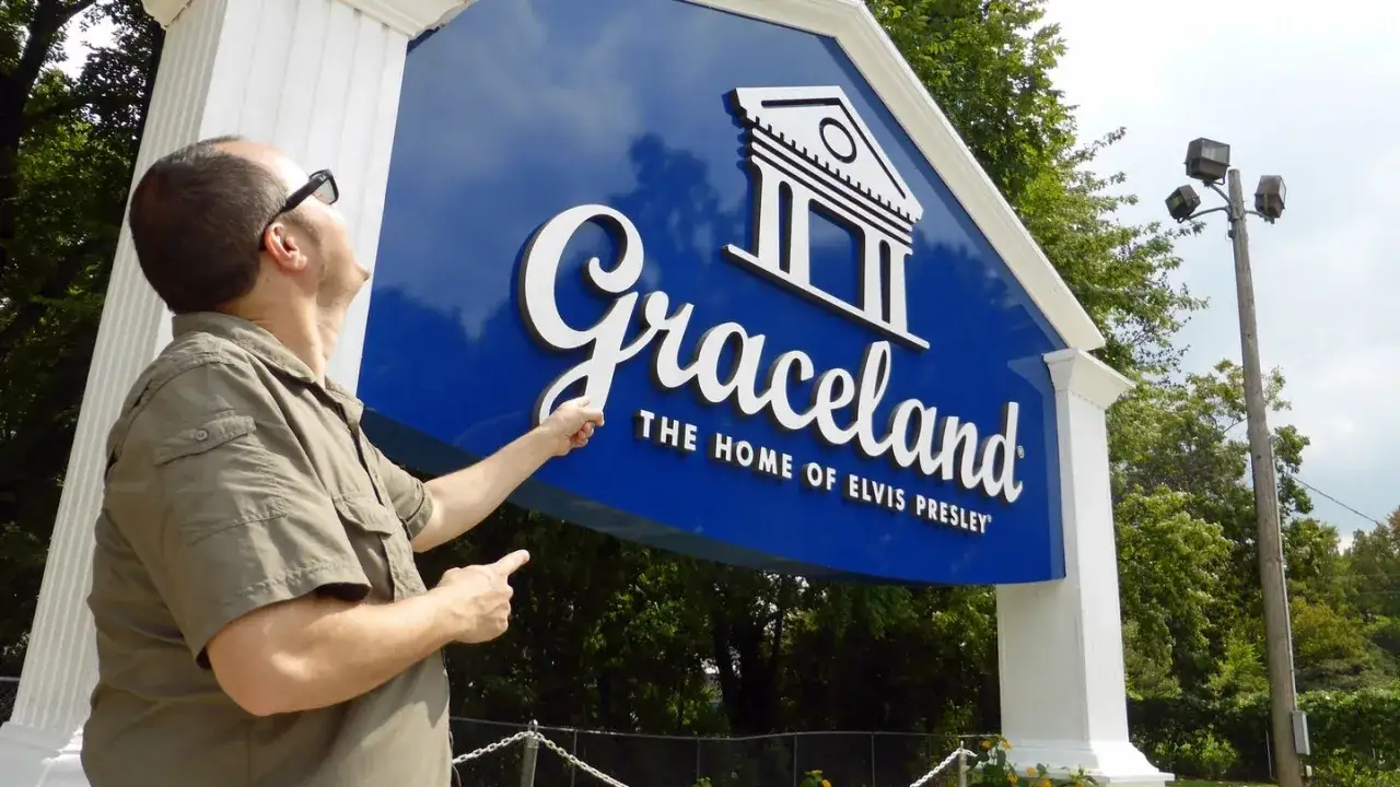 Mann zeigt auf das Graceland-Schild, das Zuhause von Elvis Presley. Ein Denkmal für das Vermögen von Elvis Presley.