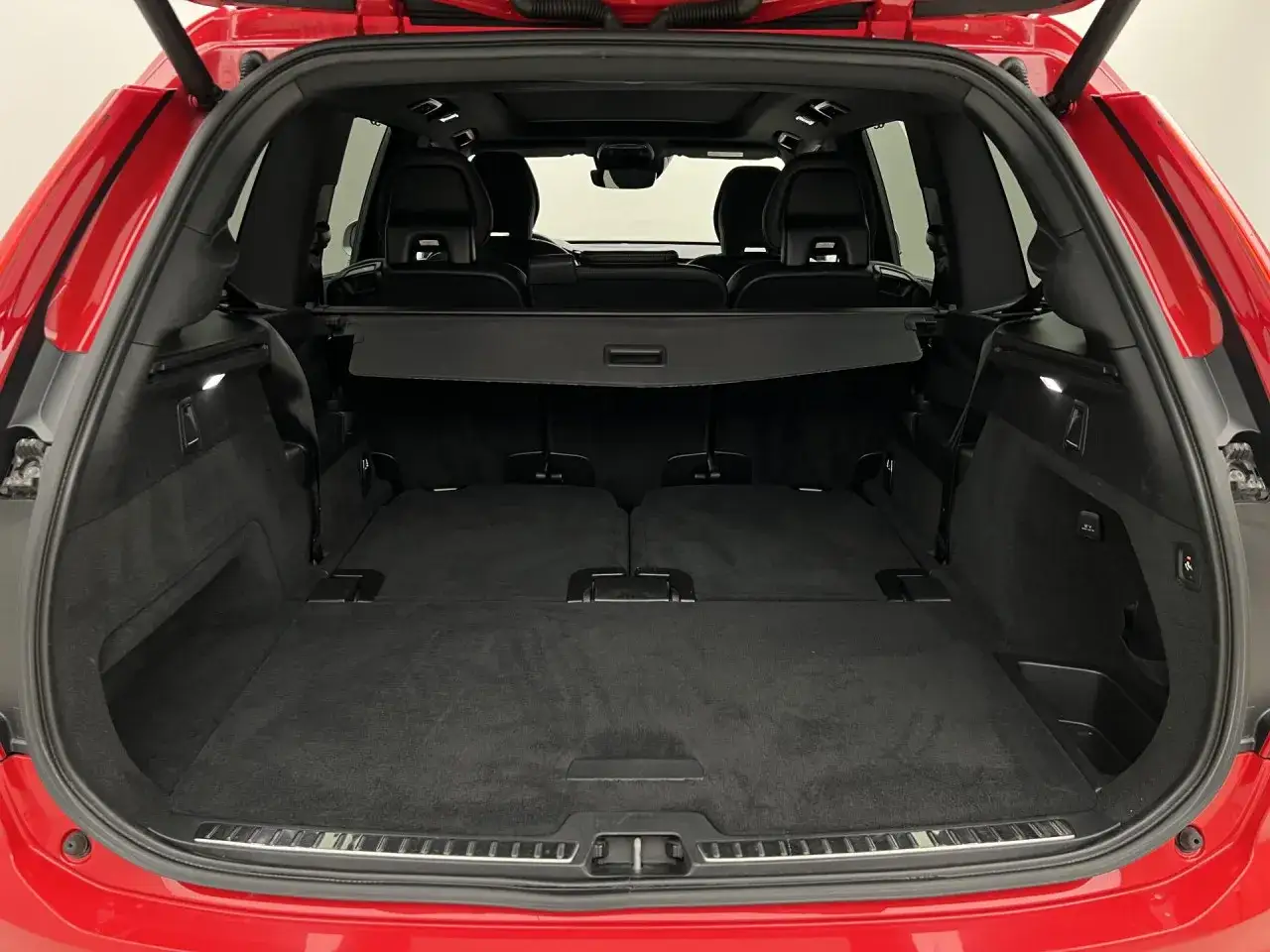 Wnętrze czerwonego Volvo XC90 podczas testu. Duży, pusty bagażnik z rozłożonymi siedzeniami w drugim rzędzie.