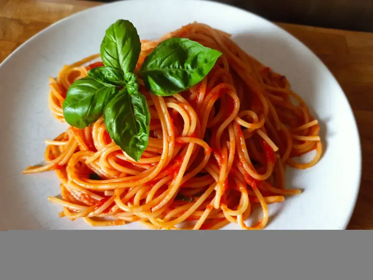 Ein Teller mit k&ouml;stlichem Spaghetti Napoli, garniert mit frischem Basilikum.