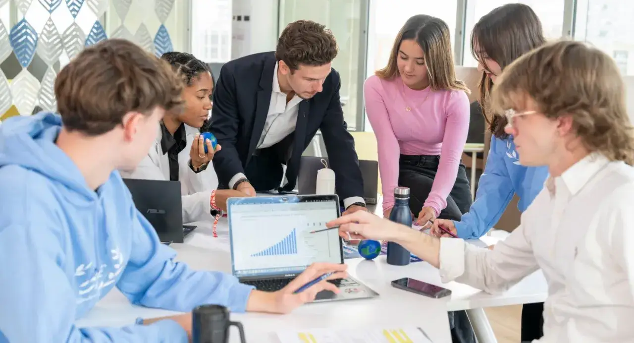 Des &eacute;tudiants analysent un graphique sur un ordinateur portable, discutant de leur **master luxe classement**.