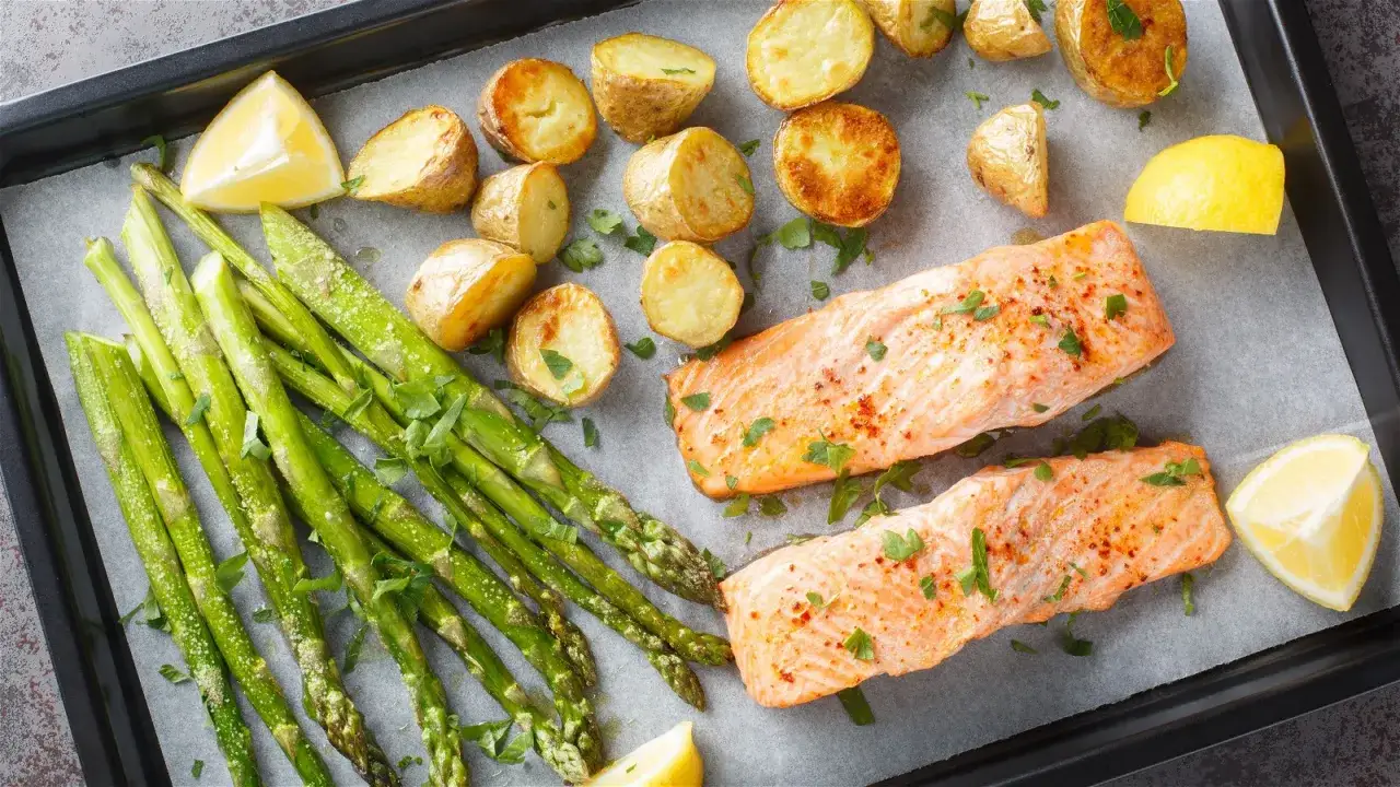 Zwei Lachsfilets mit Rosmarinkartoffeln und gr&uuml;nem Spargel, garniert mit Zitrone und Petersilie. Perfekte lachs rezepte f&uuml;r ein leichtes Abendessen.