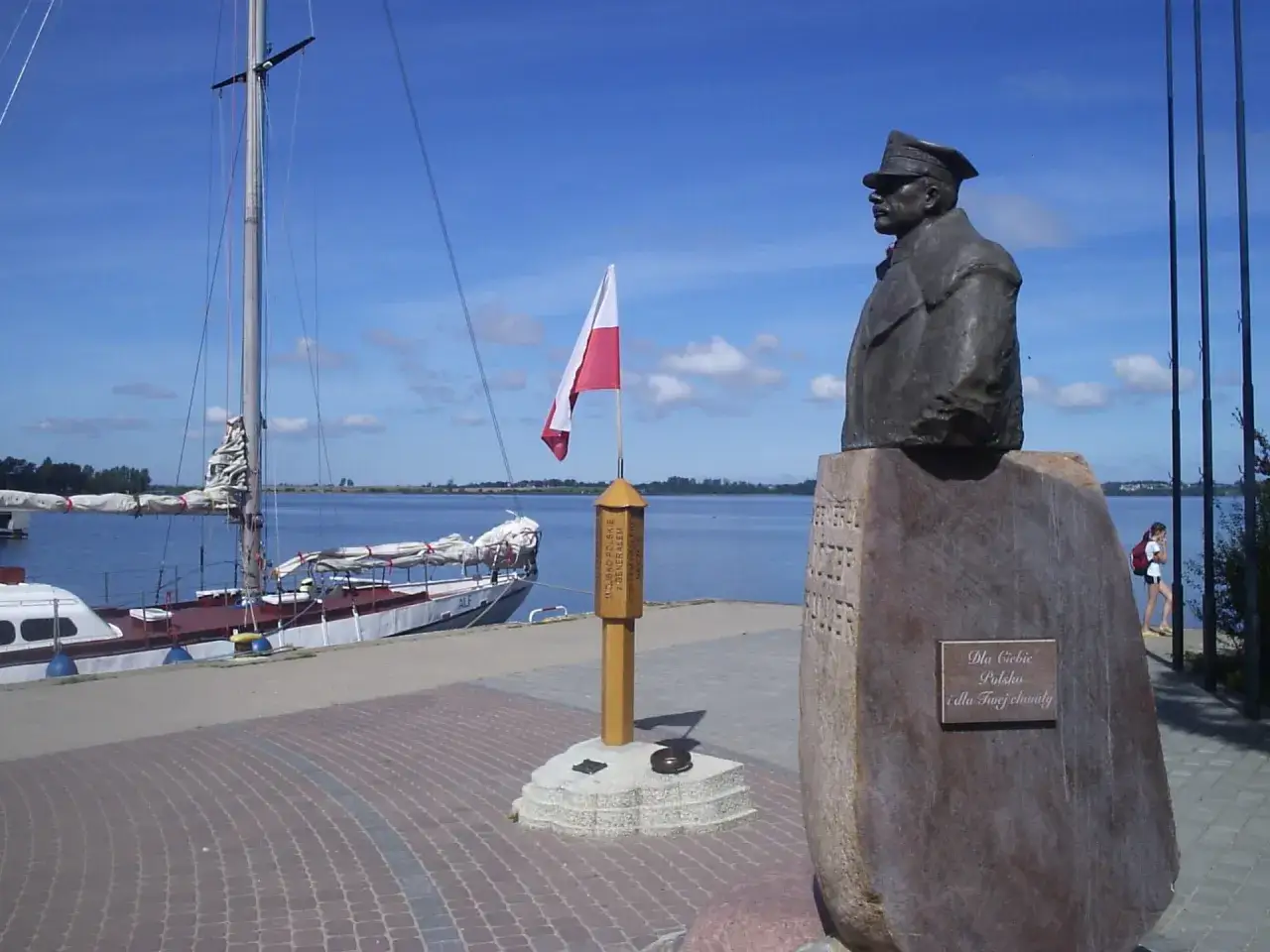 Pomnik upamiętniający zaślubiny Polski z morzem. Obok żaglowiec i polska flaga.