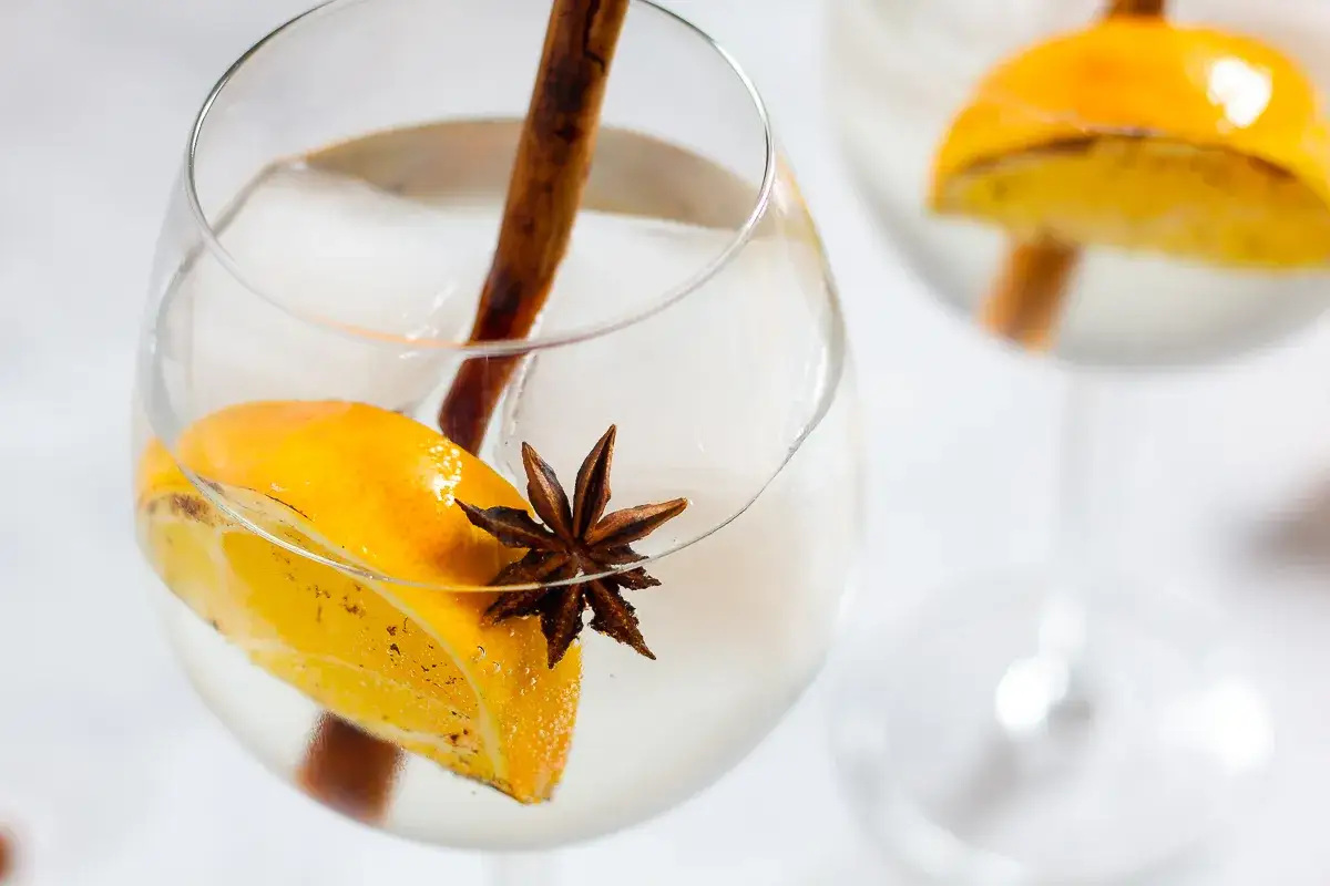 Ein Glas mit Eis, Orangenscheibe, Zimtstange und Sternanis. So k&ouml;nnte man sich vorstellen, wie schmeckt anis in einem erfrischenden Drink.