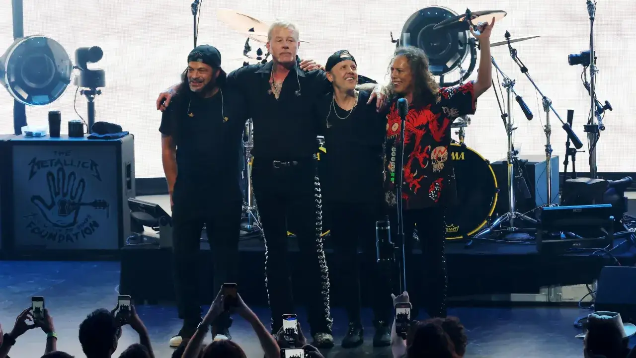 Członkowie zespołu Metallica, Lars Ulrich, James Hetfield, Kirk Hammett i Robert Trujillo, pozują na scenie.