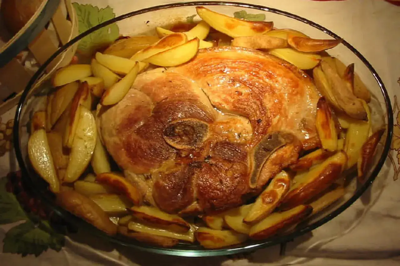 Rouelle de porc en cocotte, dorée et juteuse, accompagnée de pommes de terre rôties. Un plat réconfortant prêt à être dégusté.