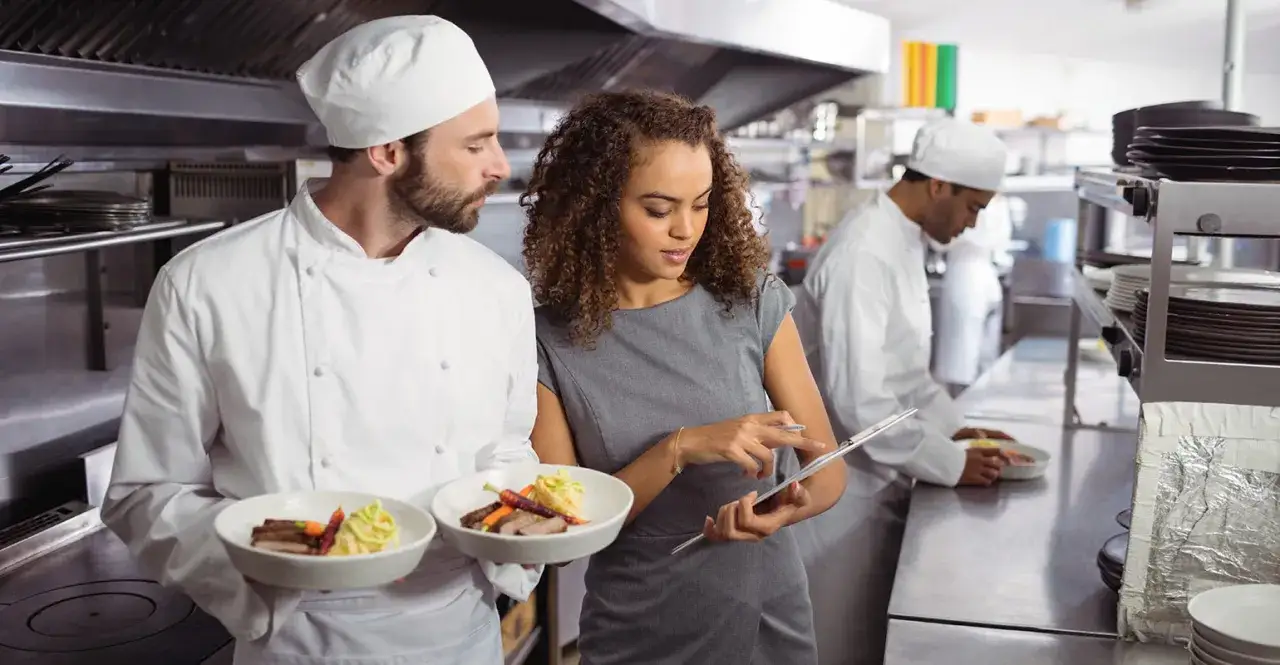 Chef y gerente revisan platos en cocina profesional. Un equipo demuestra su maestría en food and beverage.