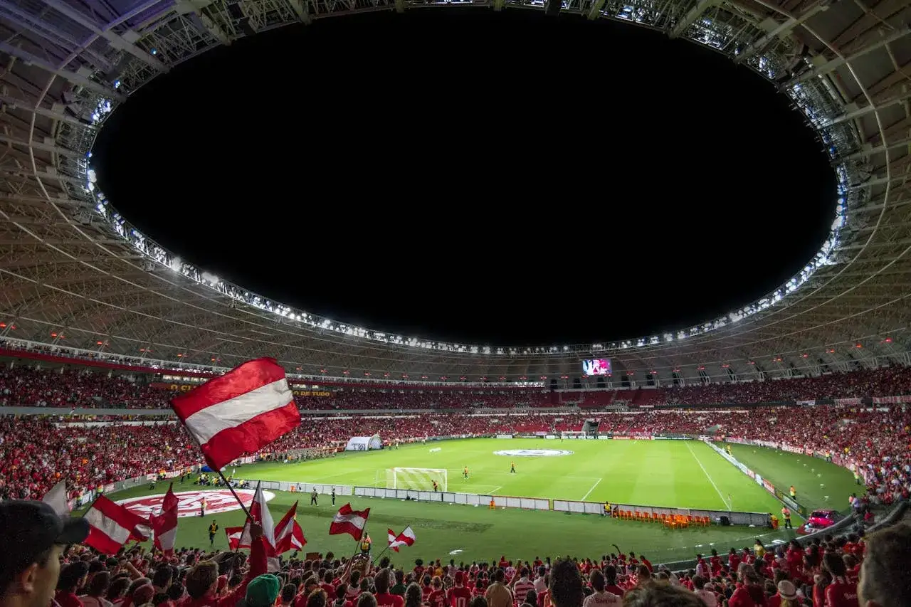 Tłum kibiców na stadionie, flagi w biało-czerwone pasy, zielona murawa i nocne niebo. Emocje podczas eliminacji do Ligi Konferencji.