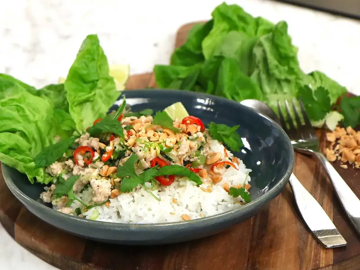 En skål med ris och kycklingfärs, toppad med jordnötter, chili och koriander. Perfekt för ett snabbt larb recept.