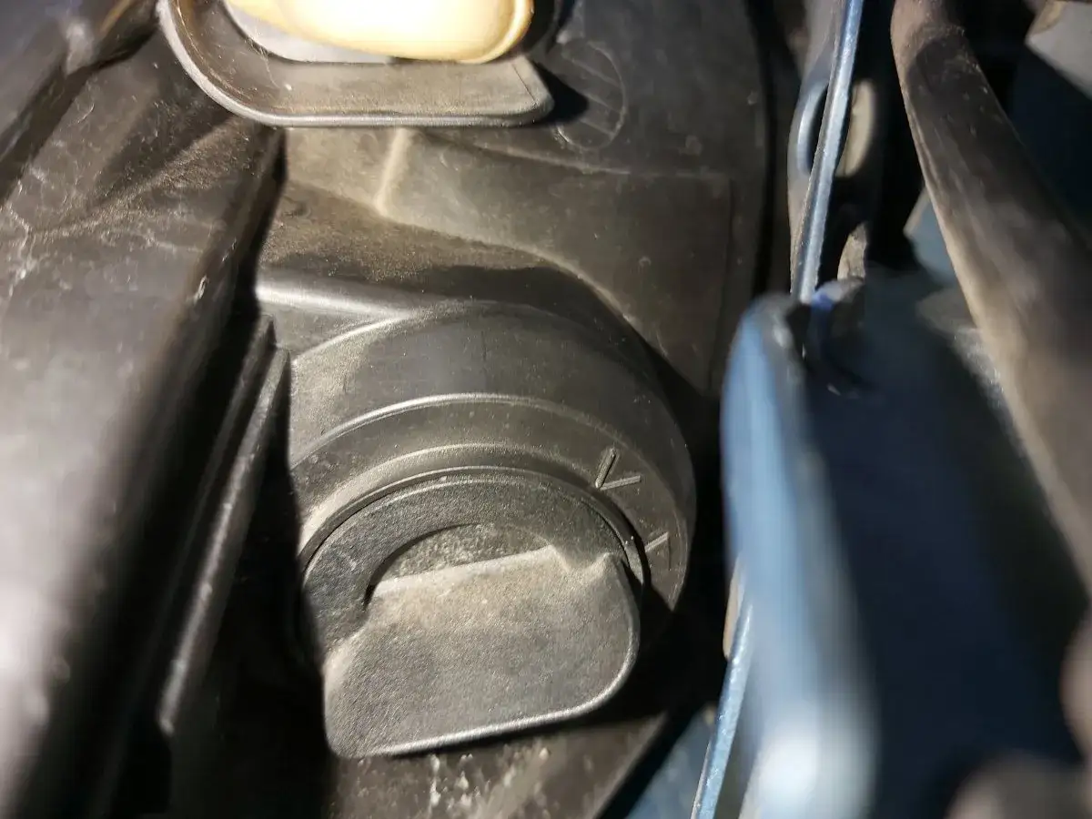 Opel Meriva B wymiana żarówki mijania. Widoczny element mocowania żarówki w reflektorze.