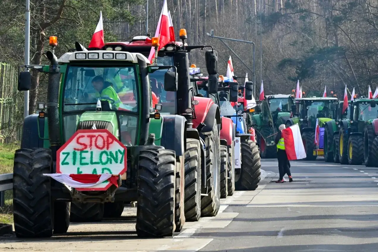 Traktory z polskimi flagami blokują drogę. Na jednym z nich znak 