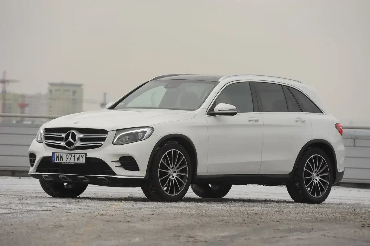 Biały Mercedes-Benz GLC 220d na tle miejskiego krajobrazu, gotowy na zimowe wyzwania.
