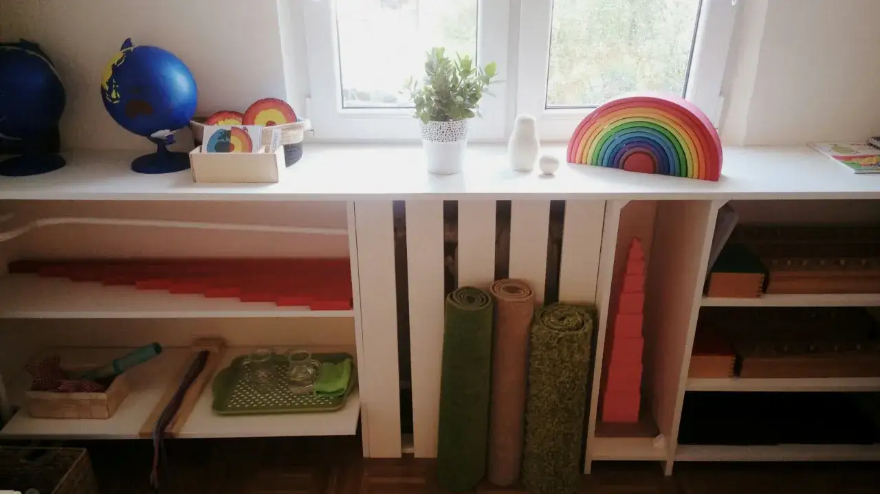 Pomoce Montessori zrób sam: koraliki, tęcza, globusy i inne materiały edukacyjne na półkach.