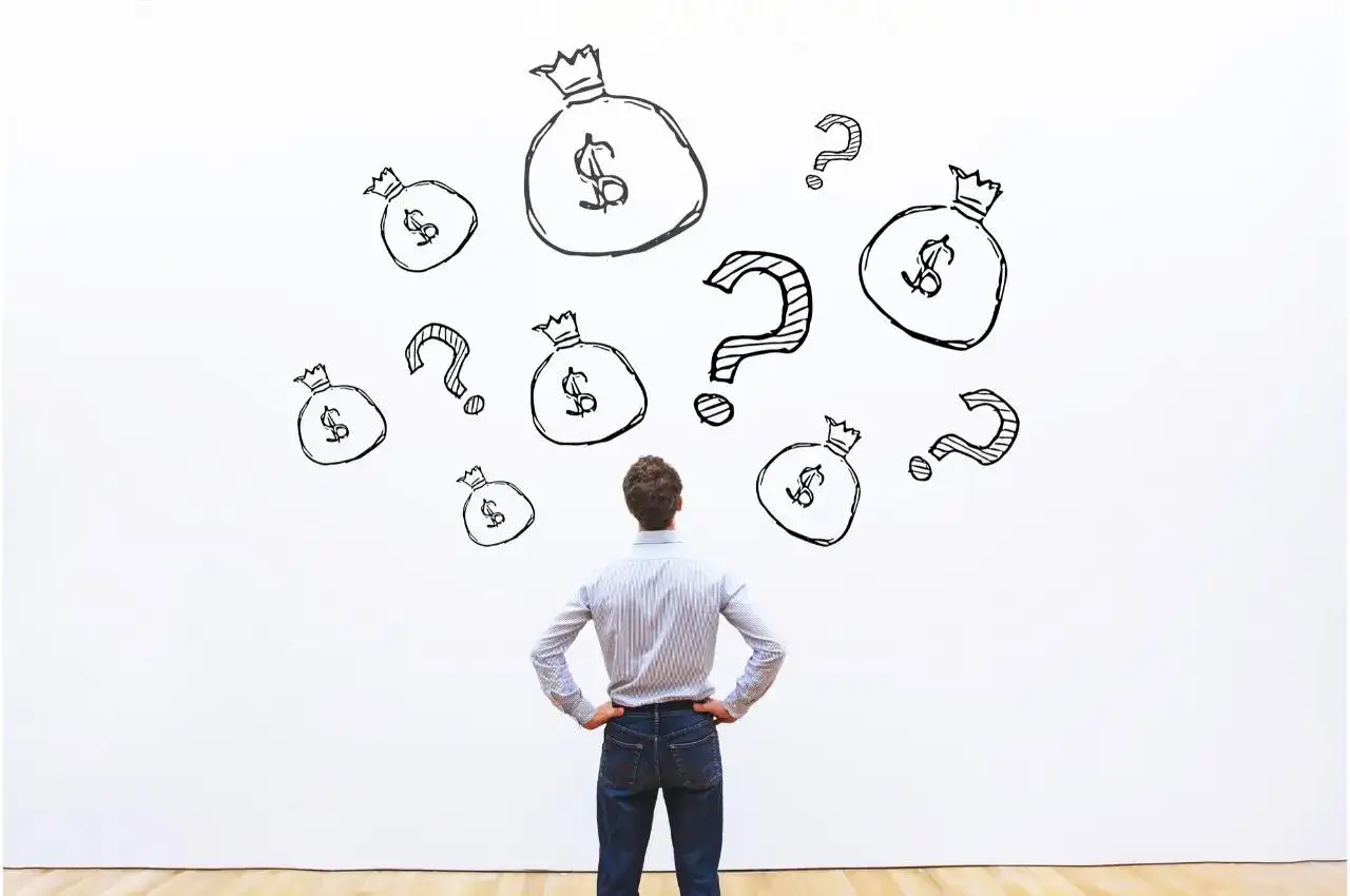 Hombre frente a bolsas de dinero y signos de interrogación, pensando cómo ganar dinero con las acciones.