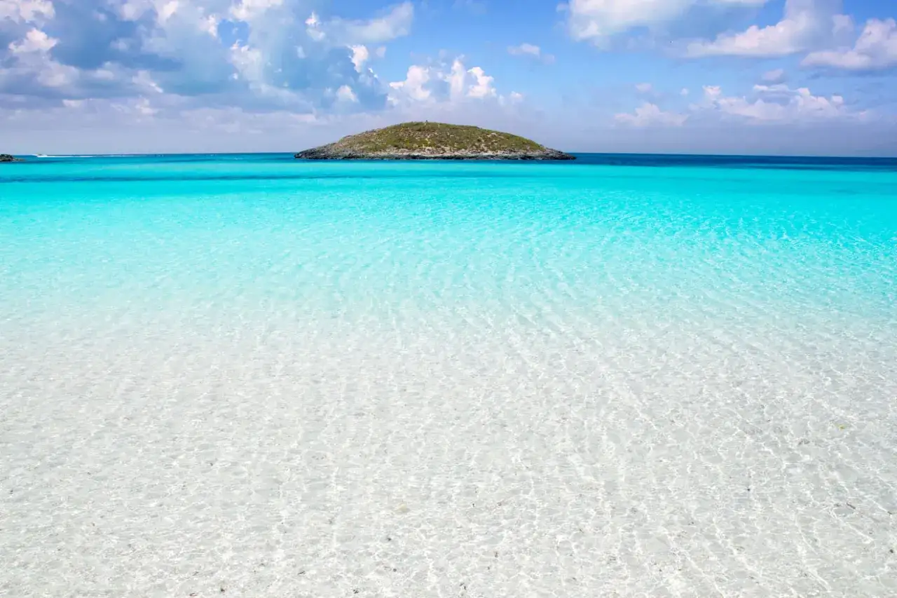 Aguas turquesas y arena blanca en Formentera. Un paraíso para descubrir qué ver en Formentera, con una pequeña isla al fondo.