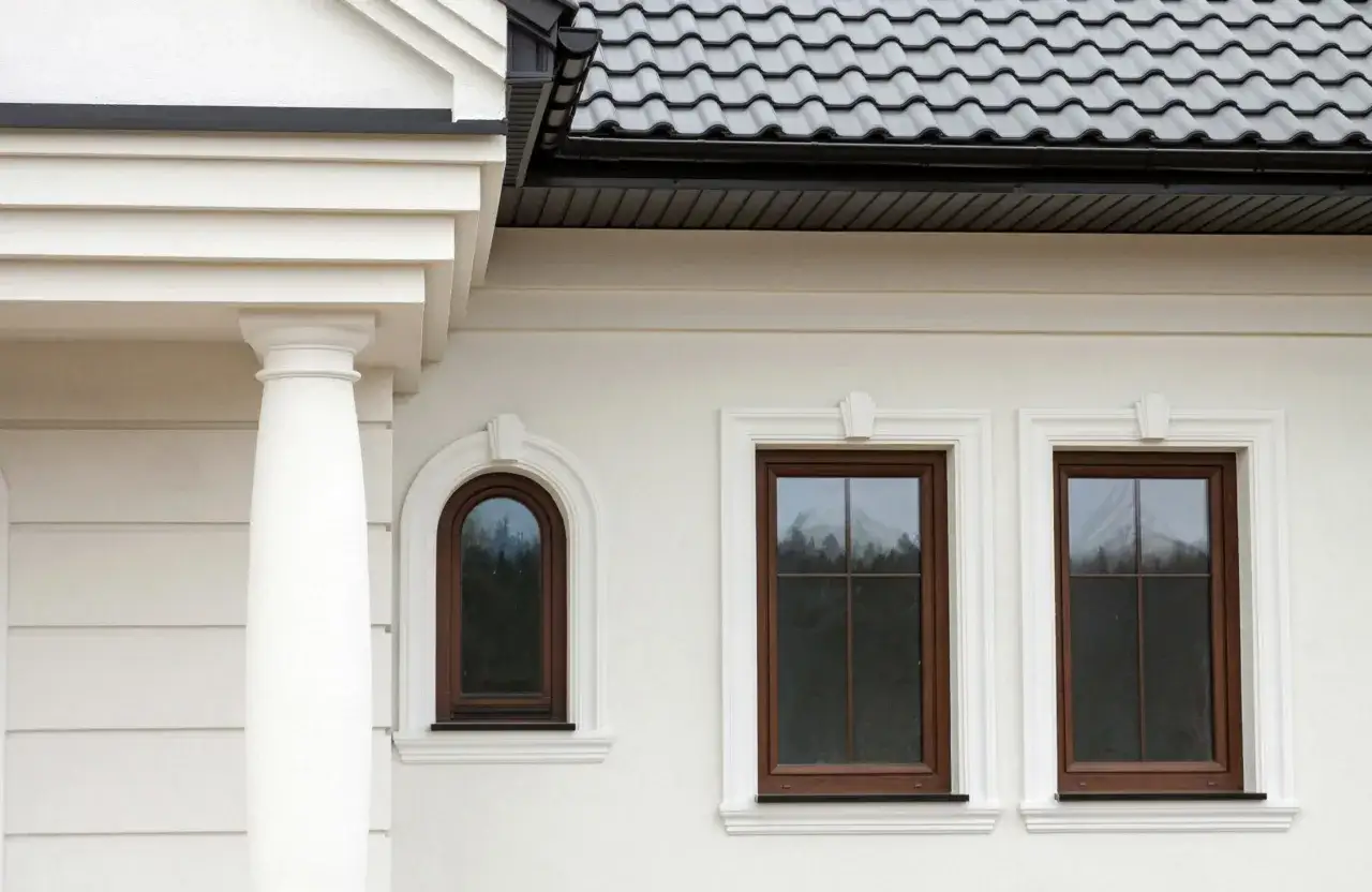 Elegancki gzyms zdobi białą elewację domu, podkreślając architekturę okien i kolumn.