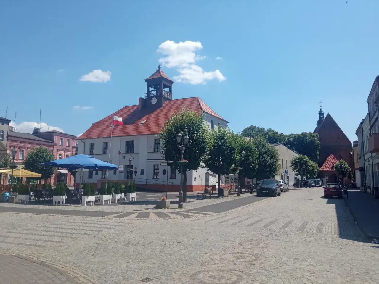 Urokliwe miasto nad Prosną z ratuszem i kościołem. Słoneczny dzień na brukowanym rynku.