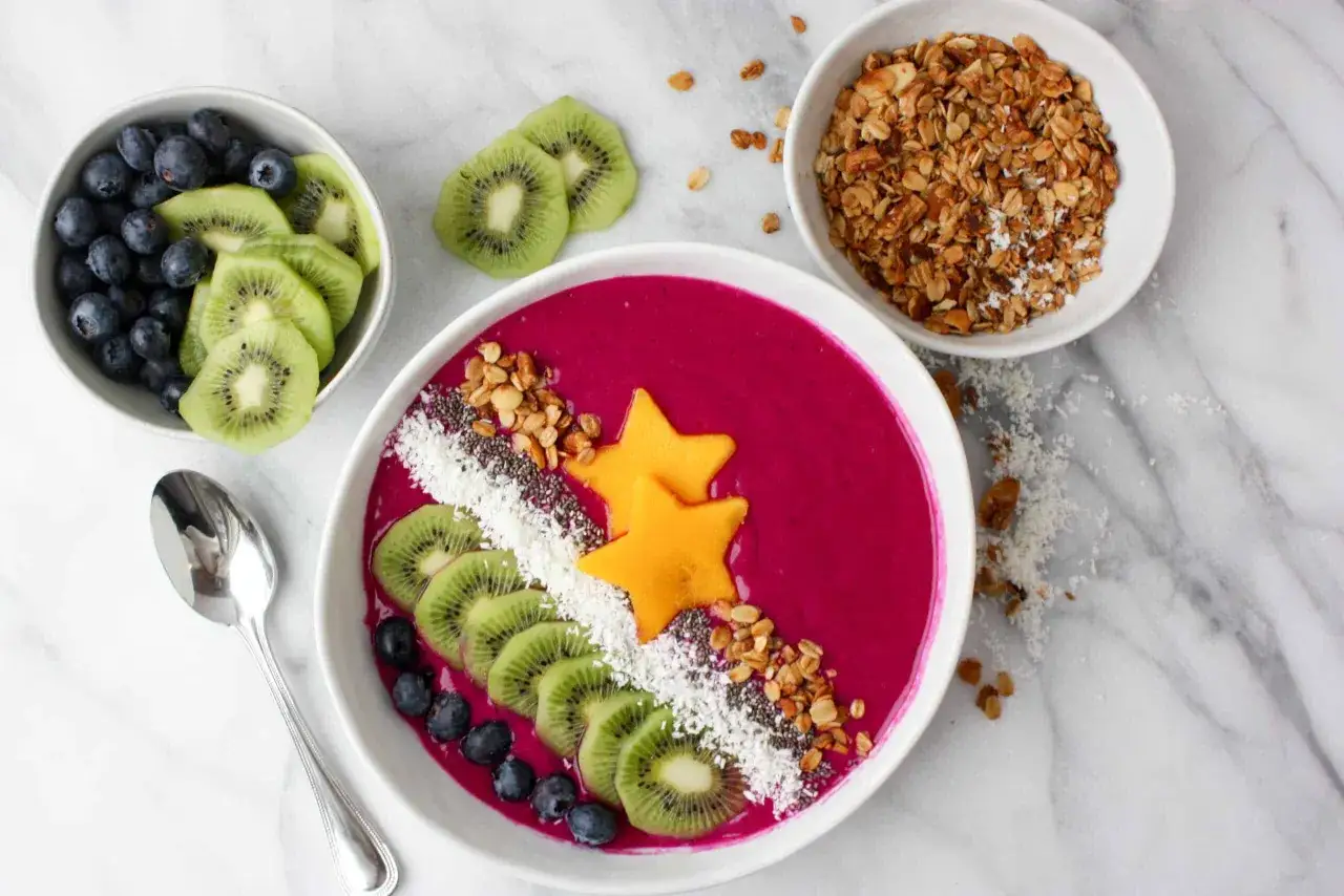 Buntes Smoothie Bowl mit Drachenfrucht, Kiwi, Blaubeeren und Granola. Ein gesundes Frühstück, das Energie spendet.