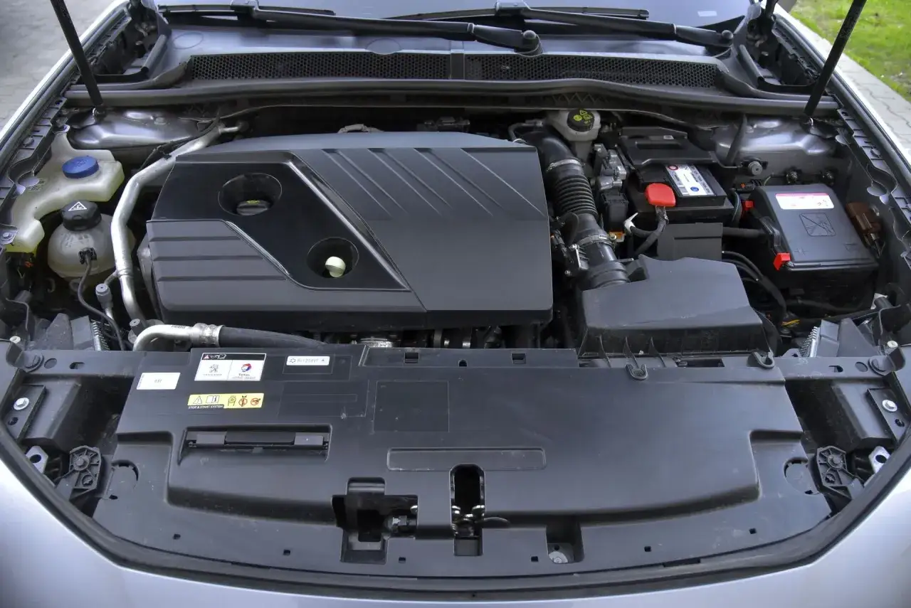 Silnik Peugeot 508 po teście. Widoczny akumulator, osłona silnika i elementy układu dolotowego.