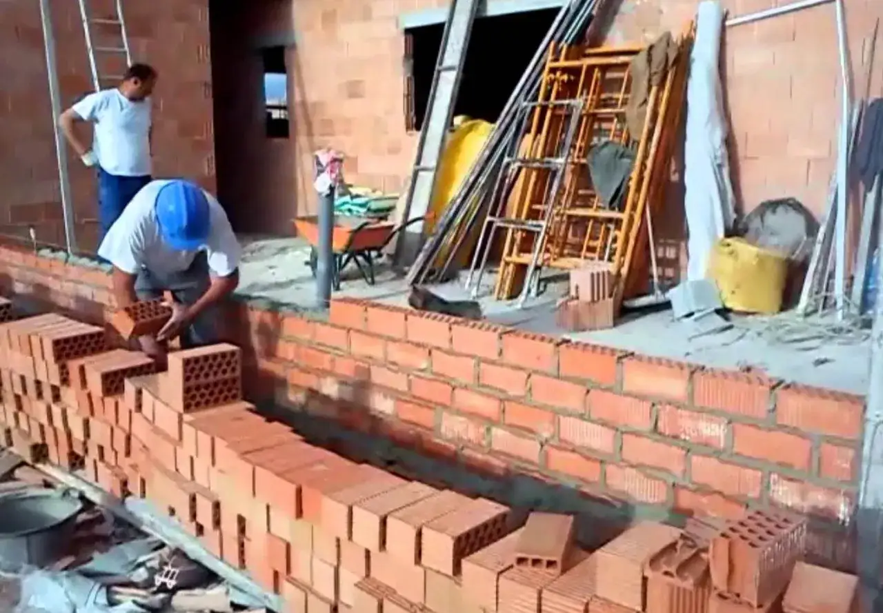 Obrero coloca ladrillos para construir diferentes tipos de muros de ladrillo. Andamios y materiales de construcci&oacute;n en el sitio.