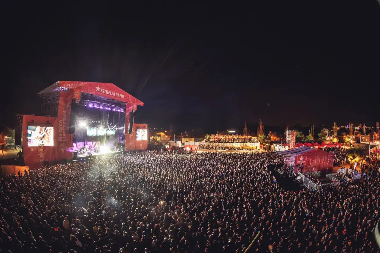 Un'enorme folla partecipa al Mallorca Live Festival, illuminata da un palco imponente e schermi giganti.