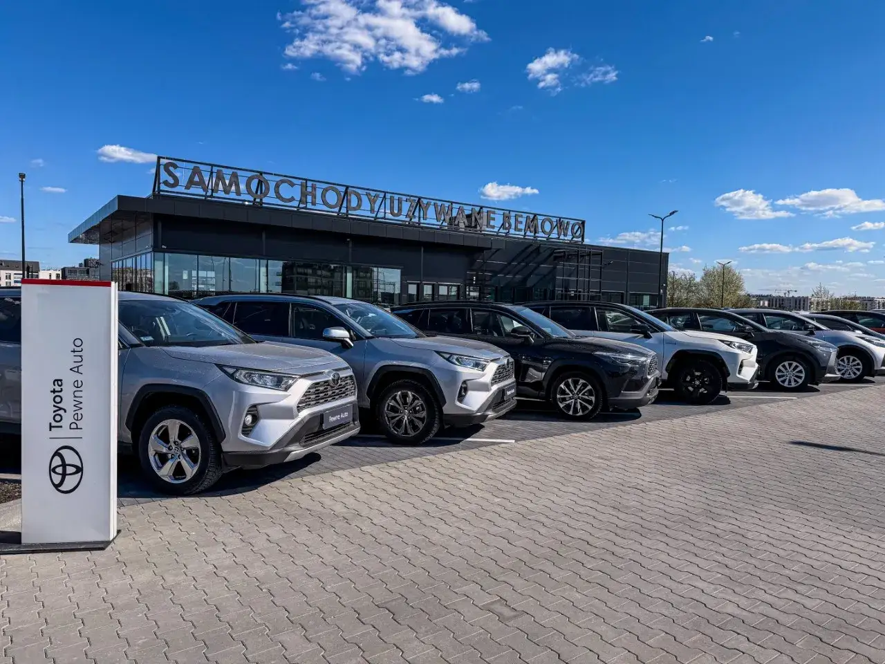 Rząd lśniących Toyota używane z salonu, zaparkowanych przed budynkiem z napisem