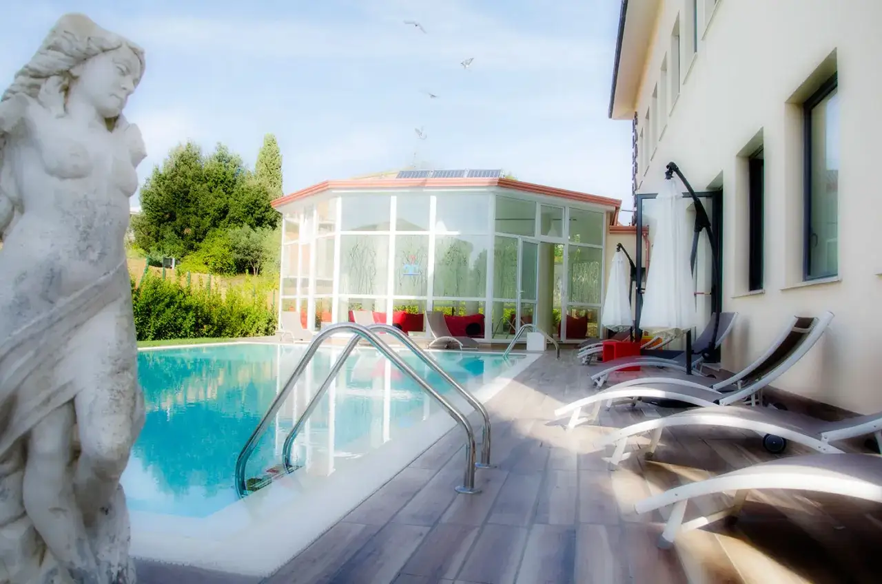 Statua classica vicino alla piscina, con un edificio moderno e un giardino lussureggiante. Un luogo ideale per rilassarsi a Gambassi Terme.