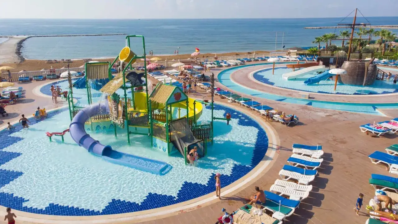 Wodne szaleństwo w Eftalia Ocean! Dzieci zjeżdżają z kolorowych zjeżdżalni, a w tle widać spokojny **eftalia ocean**.