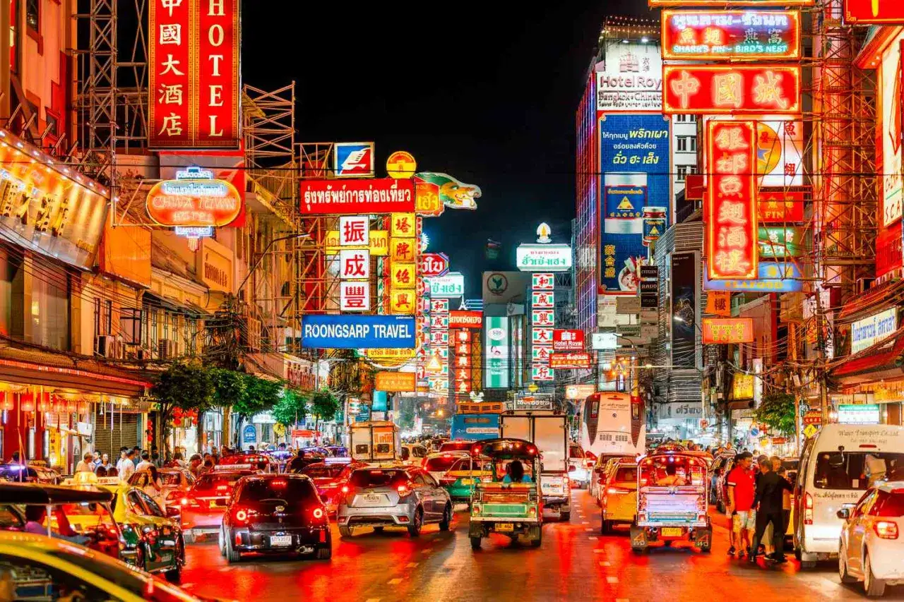 En livlig stad i Asien p&aring; natten, med neonskyltar och trafik.