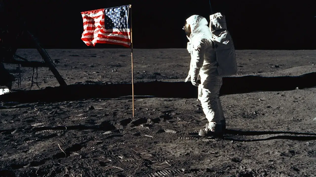 En astronaut st&aring;r bredvid en amerikansk flagga p&aring; m&aring;nen. Det &auml;r en ikonisk bild som visar buzz p&aring; m&aring;nen.